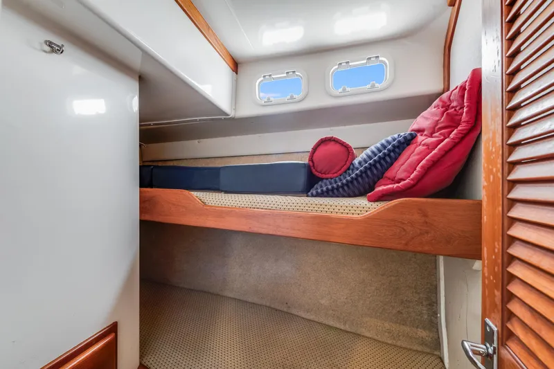  Yacht Photos Pics Cozy cabin interior of 2000 Cabo Convertible boat with bunk beds and porthole windows.