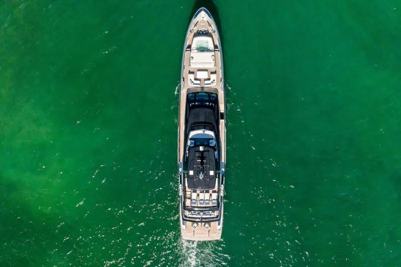 Tenacious Yacht Photos Pics Aerial view of 2025 Riva 130' Bellissima yacht cruising in clear green waters.