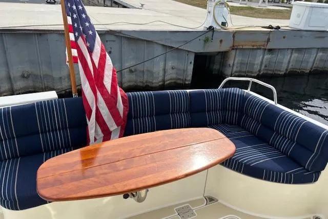  Yacht Photos Pics 2015 Sabre 42 Salon Express boat with striped seating and wooden table, docked by the water.