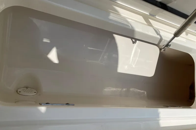 Fins Up Yacht Photos Pics 2017 Boston Whaler 320 Vantage storage compartment, open and empty, with sunlight casting shadows.