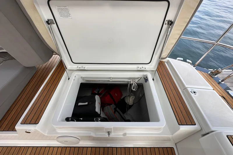Imagine Yacht Photos Pics Open storage compartment on 2017 Jeanneau 64 yacht with wooden deck and safety equipment.