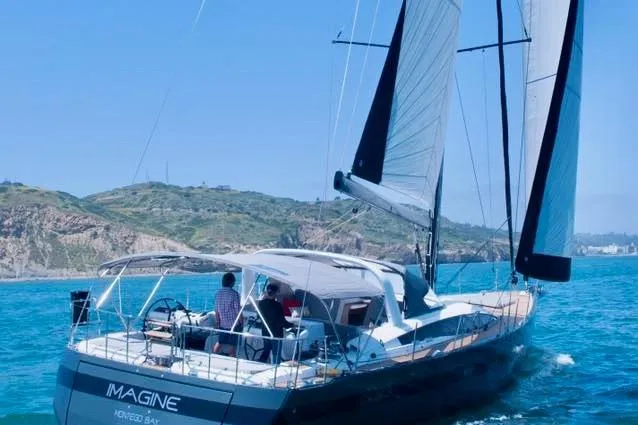 Imagine Yacht Photos Pics 2017 Jeanneau 64 sailboat "Imagine" cruising near a scenic coastline.