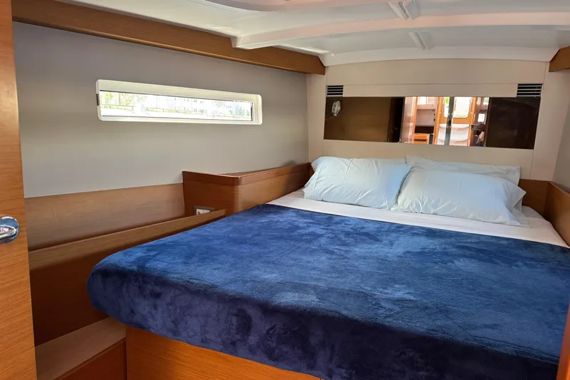 Reventador Yacht Photos Pics Cozy cabin interior of 2018 Jeanneau Sun Odyssey 440 with plush bedding and wooden accents.