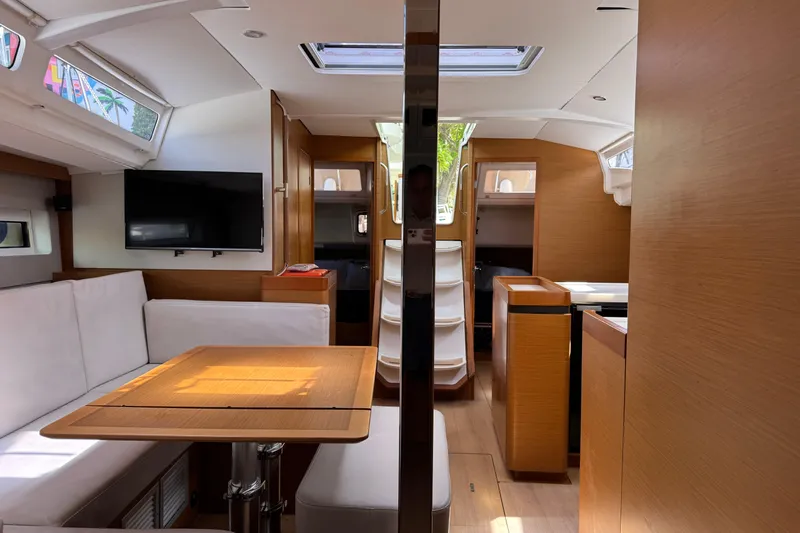 Reventador Yacht Photos Pics Interior of 2018 Jeanneau Sun Odyssey 440 yacht with modern wood finish and seating area.
