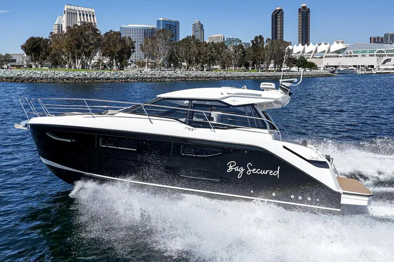 Bag Secured Yacht Photos Pics 2023 Bavaria SR36 yacht cruising in a city harbor with modern skyline backdrop.