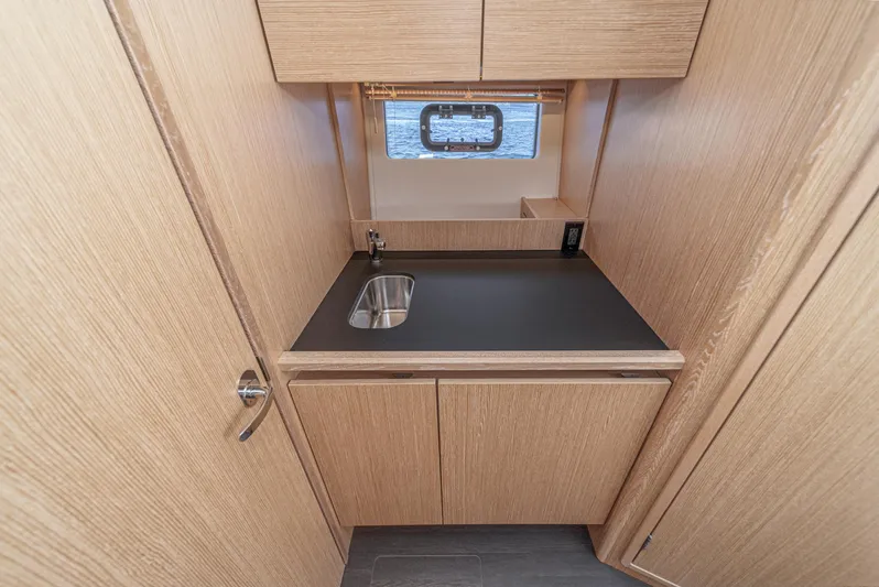 Bag Secured Yacht Photos Pics 2023 Bavaria SR36 yacht interior with compact wooden kitchenette and small window.