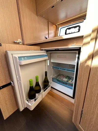 Bag Secured Yacht Photos Pics Compact fridge in 2023 Bavaria SR36 yacht, stocked with wine bottles and frozen food.