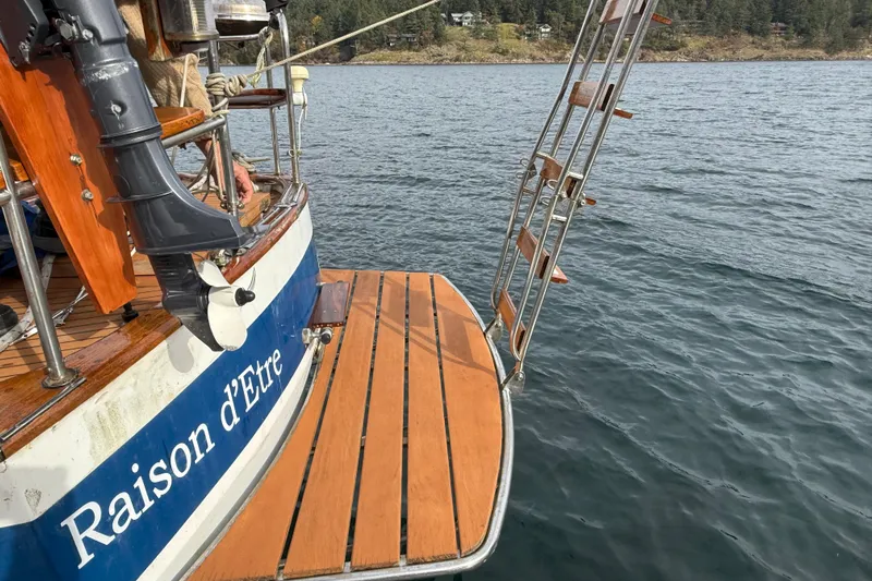 Raison D'etre Yacht Photos Pics 1988 Hallberg Rassy 42E sailboat stern with ladder and outboard motor on water.