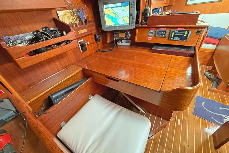 Raison D'etre Yacht Photos Pics Navigation station of 1988 Hallberg Rassy 42E yacht with chart plotter and wooden desk.