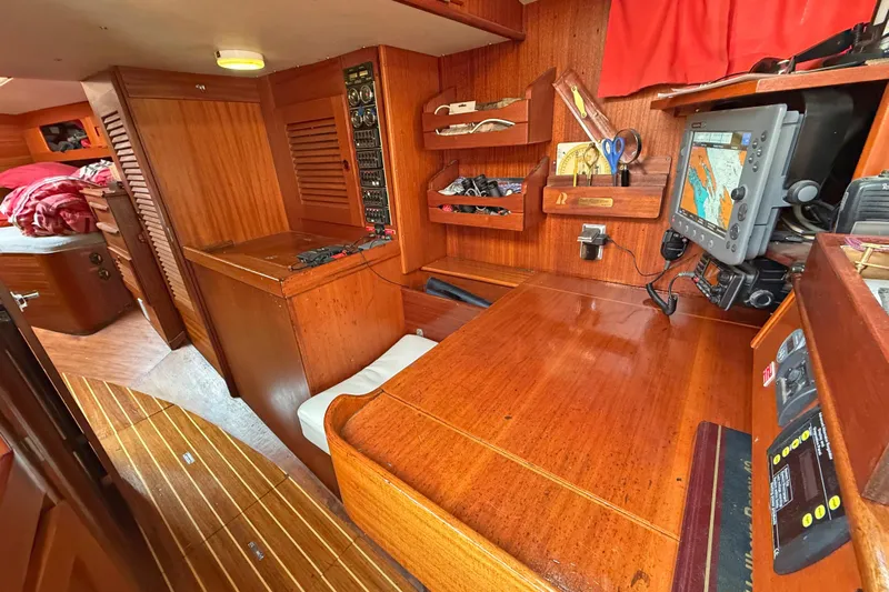 Raison D'etre Yacht Photos Pics Navigation station inside 1988 Hallberg-Rassy 42E yacht with wooden interior and chart plotter.