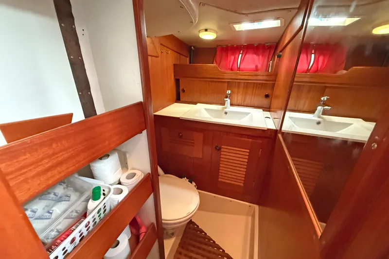 Raison D'etre Yacht Photos Pics Bathroom interior of 1988 Hallberg Rassy 42E yacht with wooden cabinetry and dual sinks.