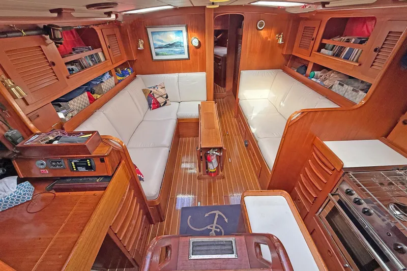 Raison D'etre Yacht Photos Pics Interior of 1988 Hallberg Rassy 42E yacht with wooden finish and white seating.