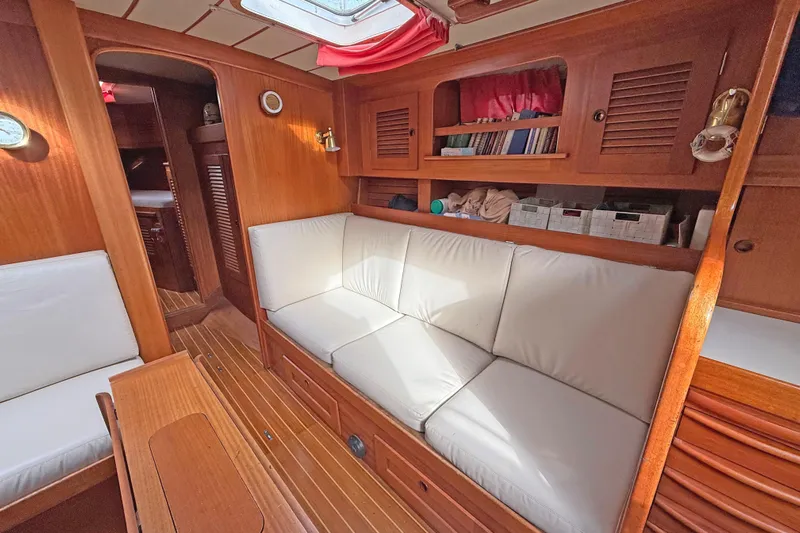 Raison D'etre Yacht Photos Pics Interior of 1988 Hallberg Rassy 42E yacht with wooden finish and white seating.