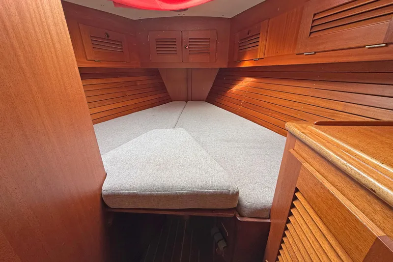 Raison D'etre Yacht Photos Pics Cozy cabin interior of 1988 Hallberg Rassy 42E sailboat with wooden finish and cushioned bed.