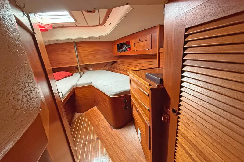 Raison D'etre Yacht Photos Pics Cozy cabin interior of 1988 Hallberg Rassy 42E sailboat with wooden finish and bedding.