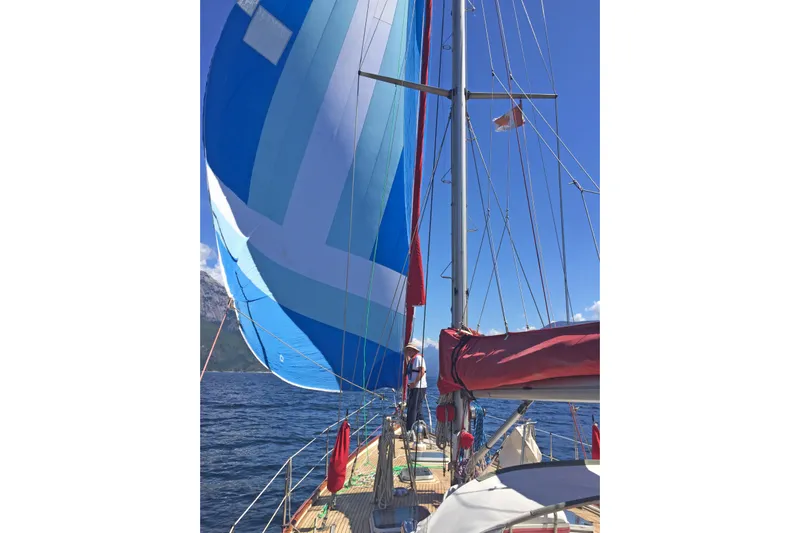 Raison D'etre Yacht Photos Pics 1988 Hallberg Rassy 42E sailboat with blue spinnaker on open water.