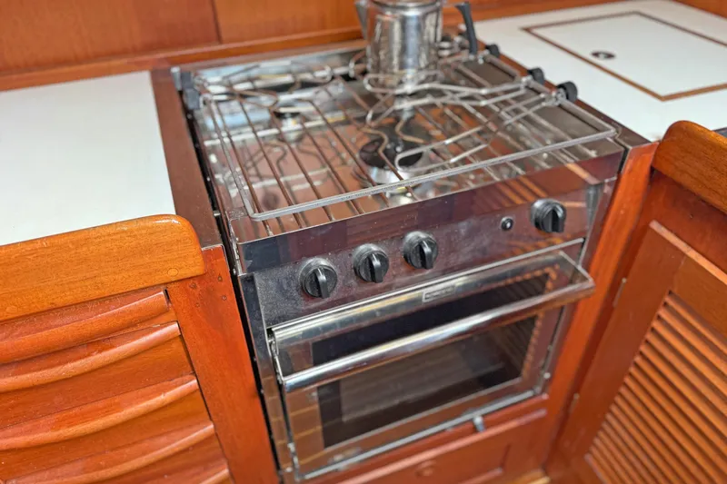 Raison D'etre Yacht Photos Pics Galley kitchen in 1988 Hallberg Rassy 42E yacht with stove and wooden cabinetry.