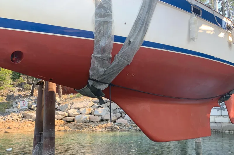 Raison D'etre Yacht Photos Pics 1988 Hallberg Rassy 42E sailboat hull in dry dock, showcasing red and white design.