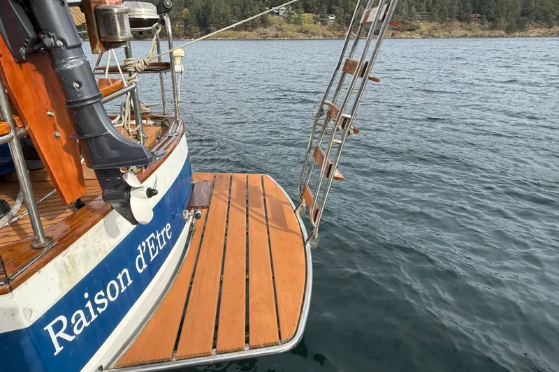 Raison D'etre Yacht Photos Pics 1988 Hallberg Rassy 42E sailboat stern with wooden deck and ladder on water.