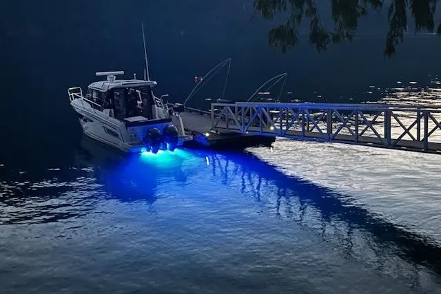  Yacht Photos Pics Jeanneau 895 Offshore 2017 boat docked with blue underwater lights at dusk.