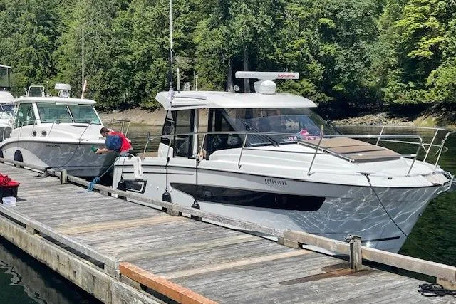  Yacht Photos Pics 2017 Jeanneau 895 Offshore docked, surrounded by lush greenery.