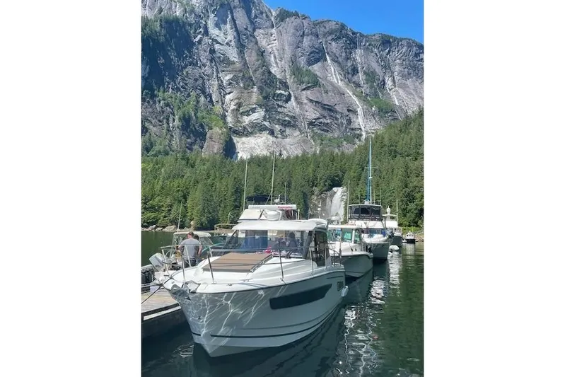  Yacht Photos Pics 2017 Jeanneau 895 Offshore docked by scenic waterfall and forested cliffs.