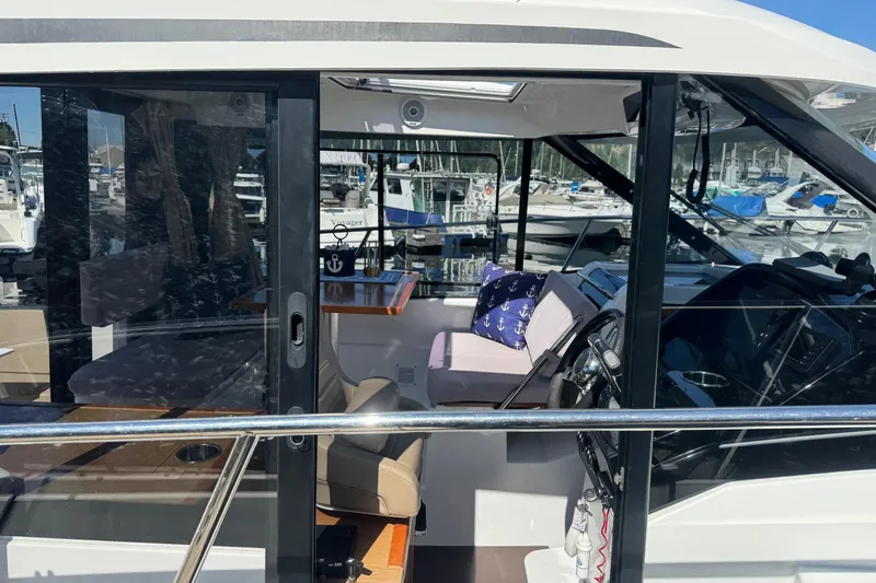  Yacht Photos Pics 2017 Jeanneau 895 Offshore boat interior with seating and steering wheel, docked at marina.