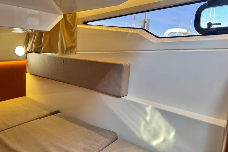  Yacht Photos Pics Interior cabin of 2017 Jeanneau 895 Offshore boat, featuring cozy seating and window view.
