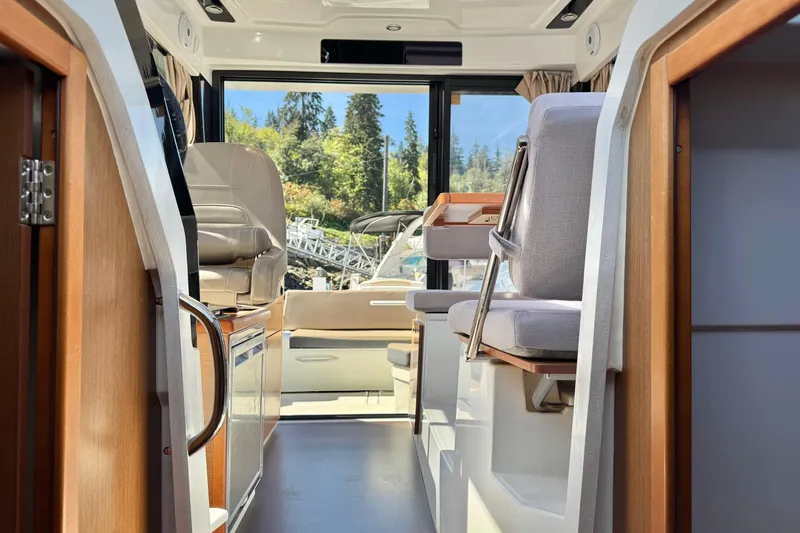  Yacht Photos Pics Interior view of 2017 Jeanneau 895 Offshore boat, featuring seating and scenic window view.