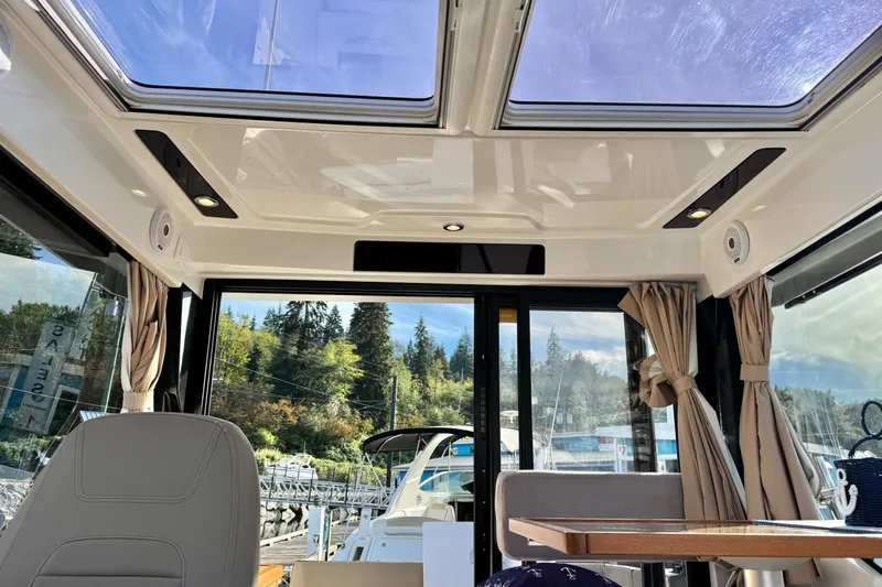  Yacht Photos Pics Interior view of 2017 Jeanneau 895 Offshore boat with sunroof and scenic marina backdrop.