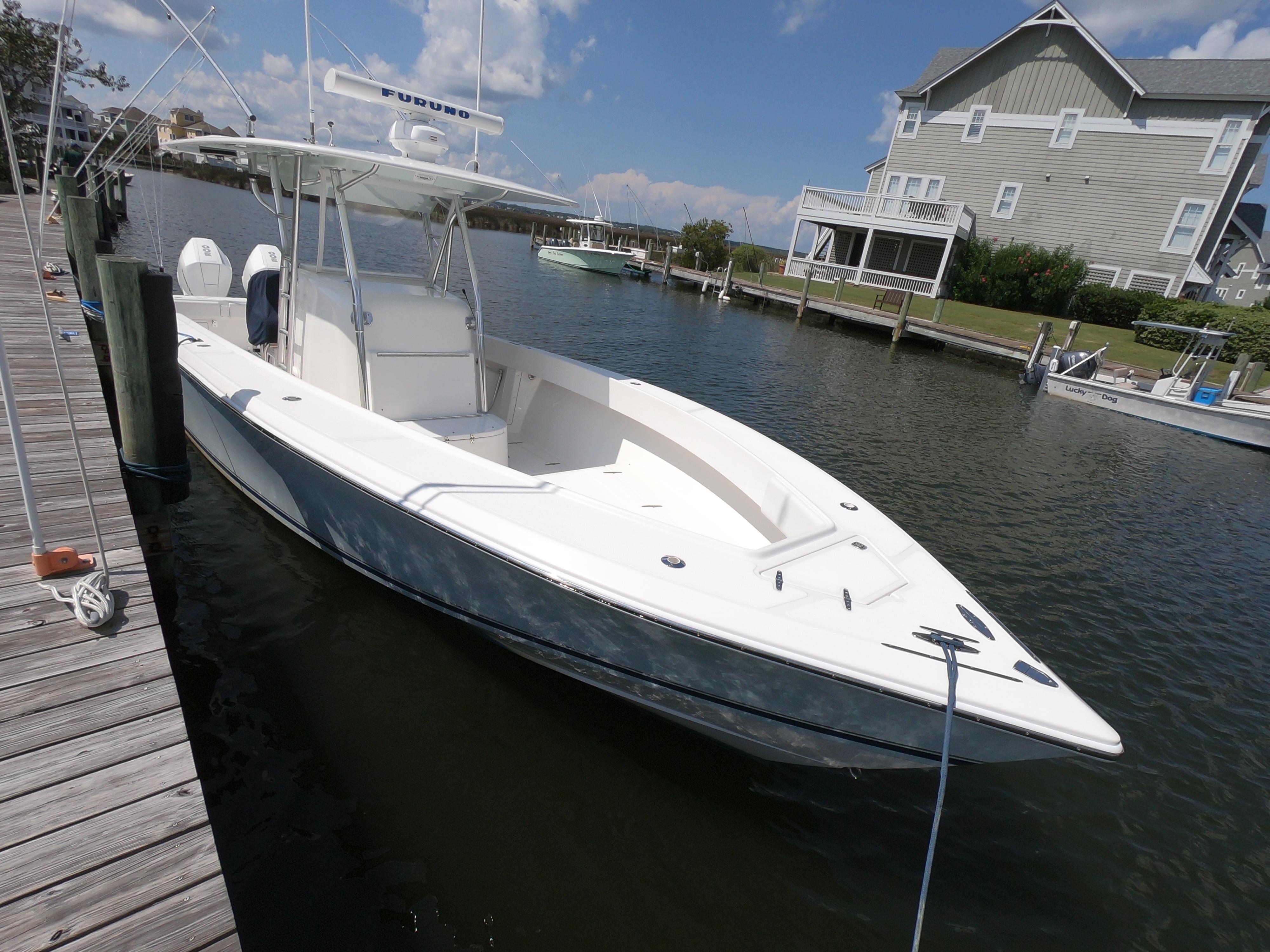 2003 Venture 34 Open boat docked by waterfront homes under a clear sky.