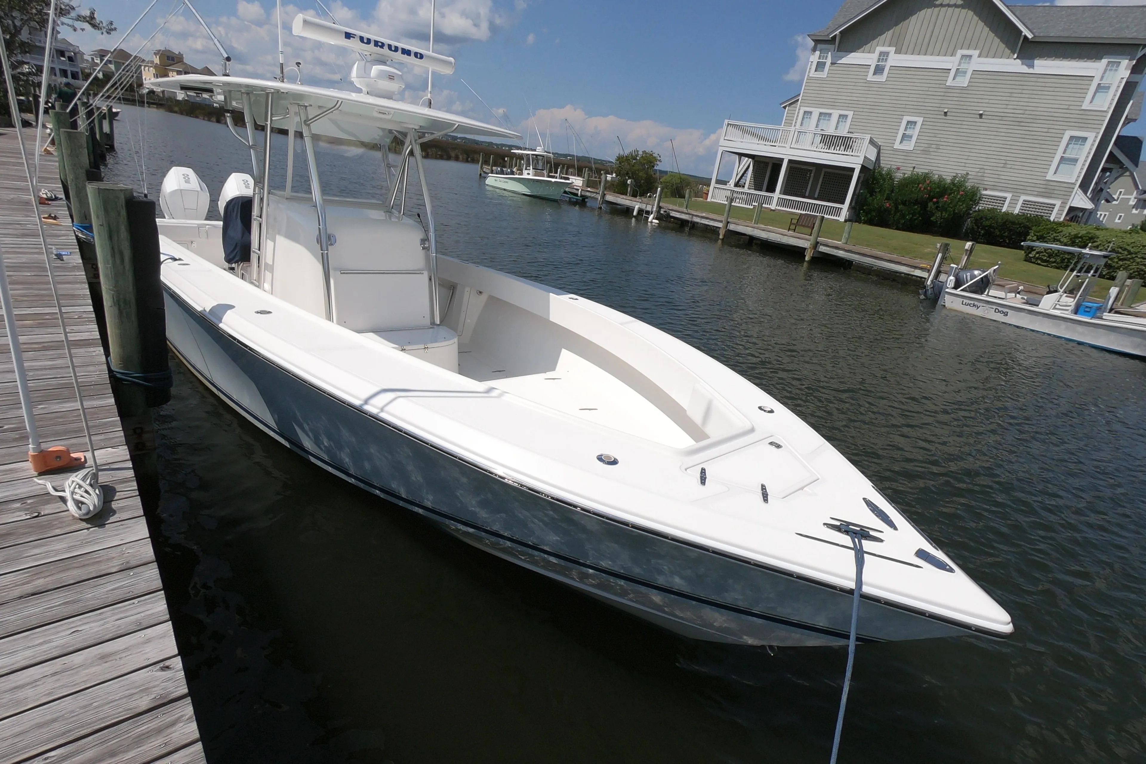 2003 Venture 34 Open boat docked by waterfront homes under a clear sky.