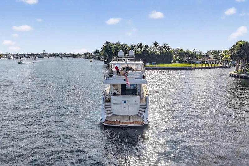 Arlene Yacht Photos Pics Luxury 2009 Horizon Flybridge yacht cruising on a sunny waterway, surrounded by lush greenery.
