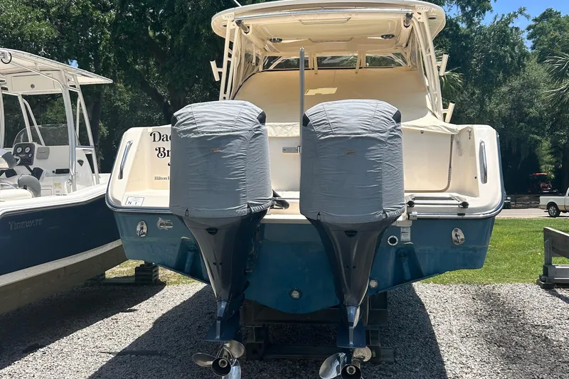 Daddy's Broke Lll Yacht Photos Pics 2020 Grady-White Canyon 306 boat with dual covered outboard motors, parked on gravel.