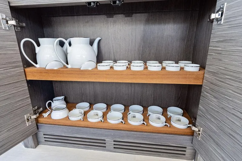 Phoenix Rising Yacht Photos Pics Cabinet with white teapots and cups on wooden shelves, Pershing 82 yacht interior.