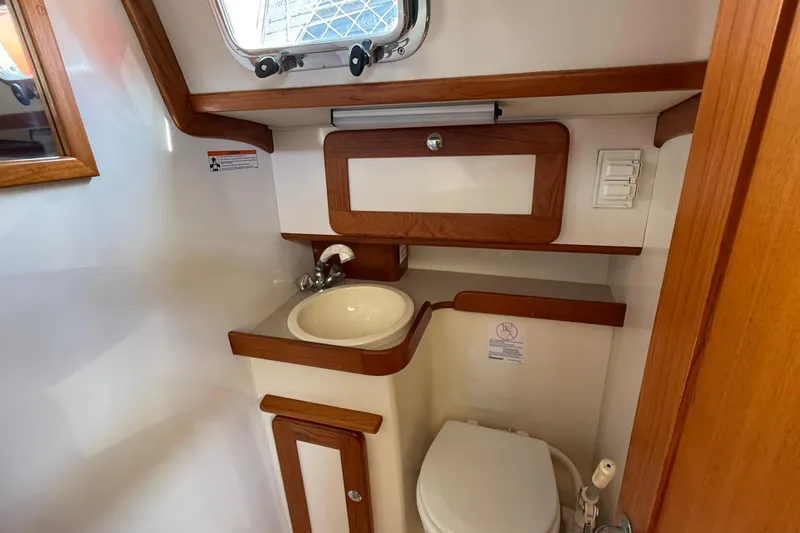 Via Yacht Photos Pics Compact bathroom in 2004 Caliber 40LRC yacht with sink, toilet, and wooden accents.
