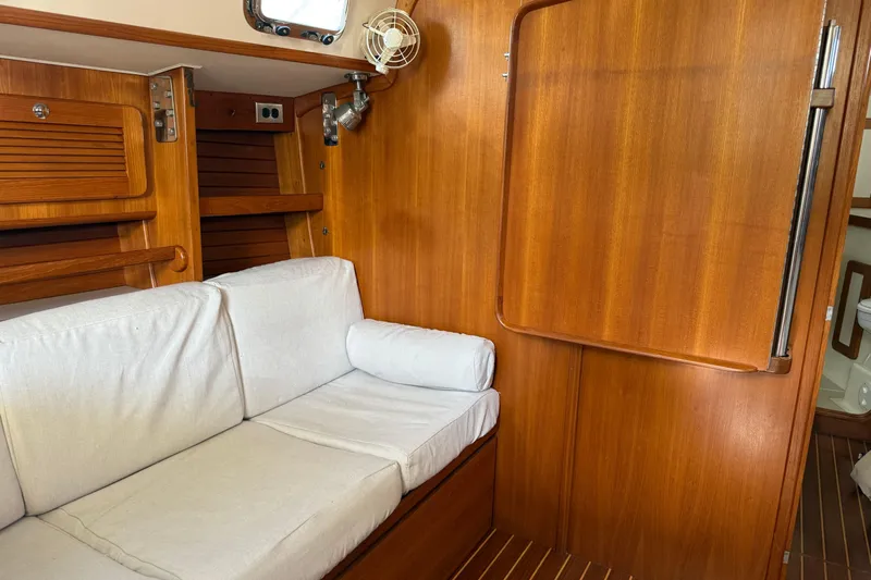 Via Yacht Photos Pics Interior of 2004 Caliber 40LRC sailboat with wooden paneling and white cushioned seating.