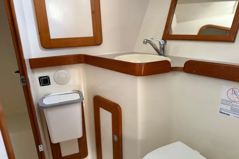 Via Yacht Photos Pics 2004 Caliber 40LRC yacht bathroom with sink, mirror, and wooden accents.