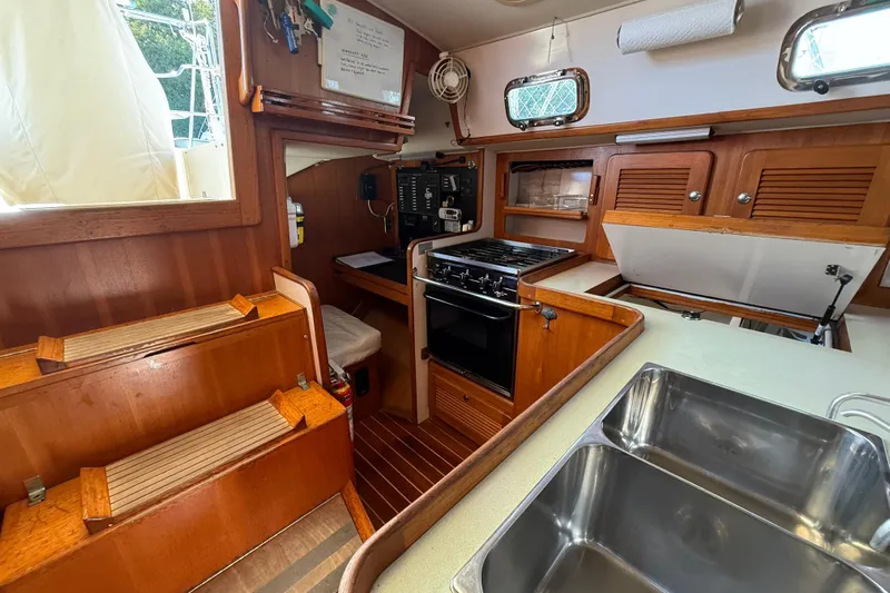Via Yacht Photos Pics Interior of 2004 Caliber 40LRC yacht, featuring a compact kitchen with wooden cabinetry.