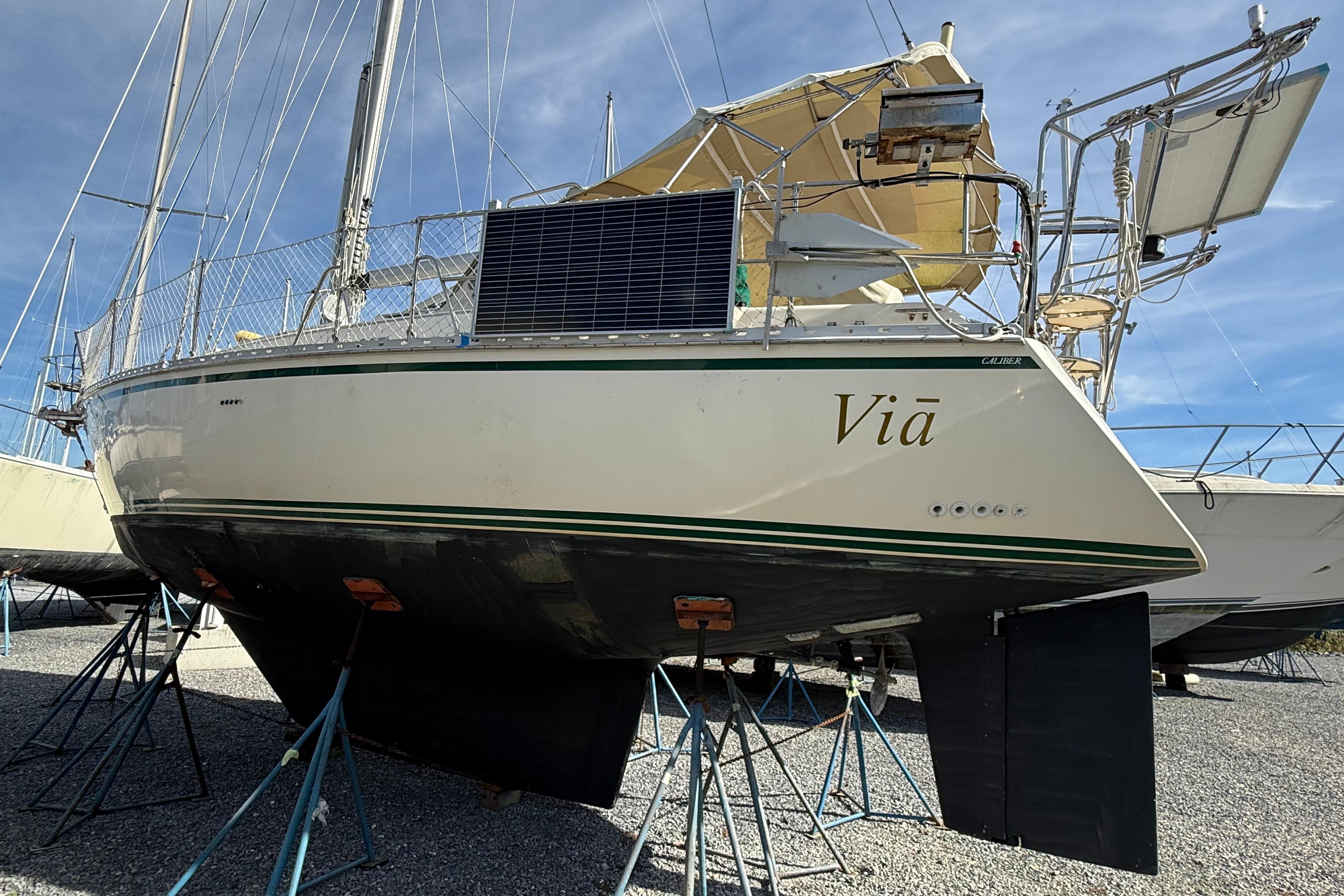 2004 Caliber 40LRC sailboat on stands, featuring solar panels and a beige canopy.