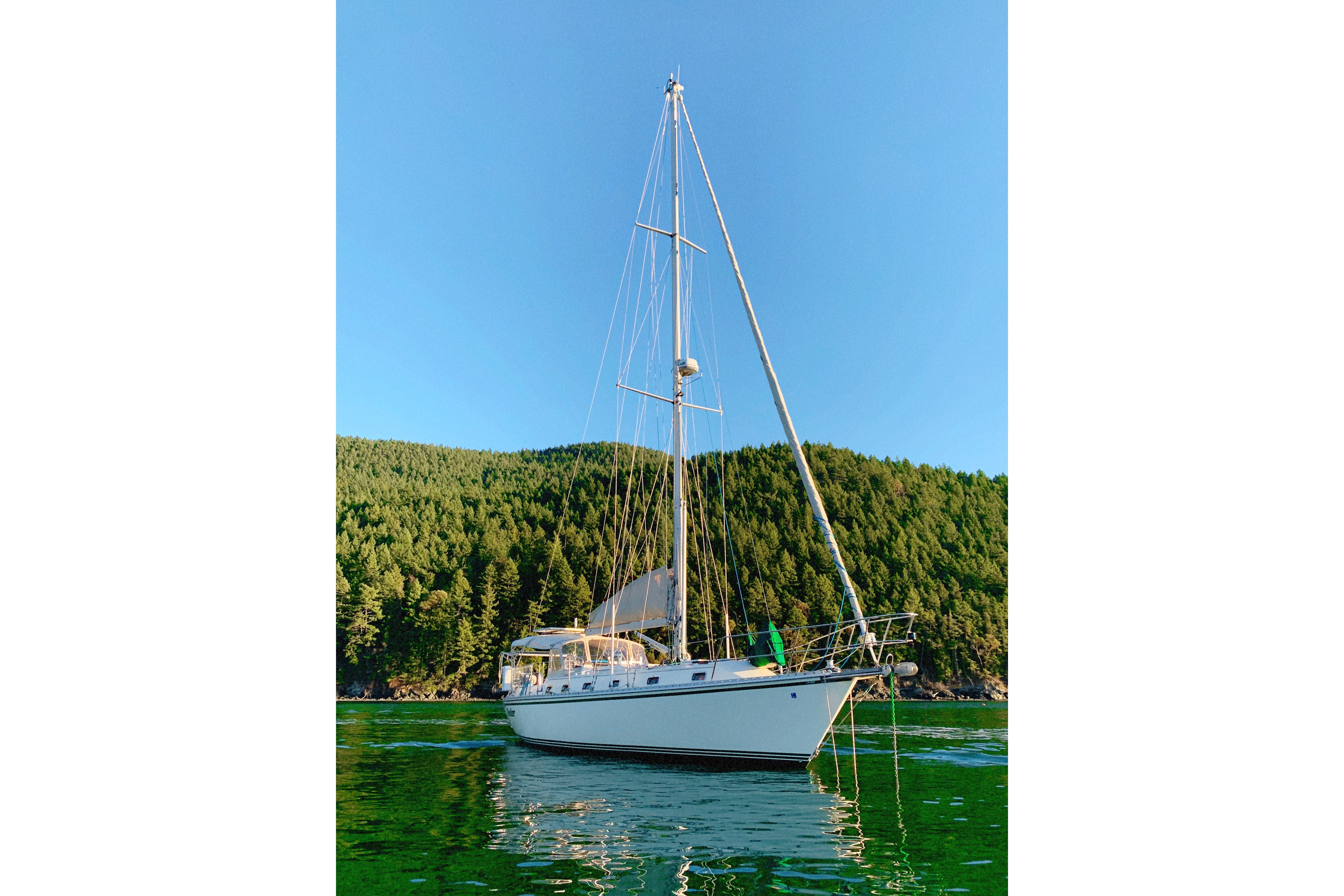 Sailboat Caliber 40LRC 2004 anchored in scenic green bay with forested hills.