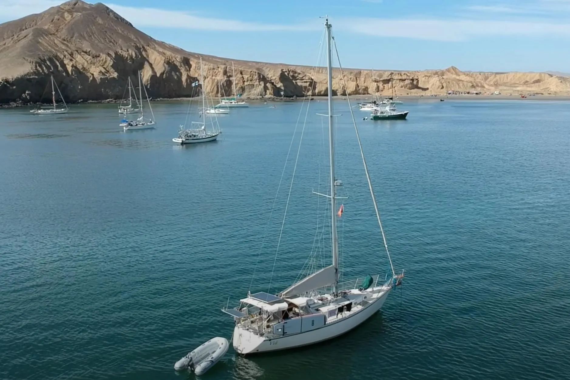 Sailboats anchored in a serene bay with rocky cliffs, featuring a 2004 Caliber 40LRC.