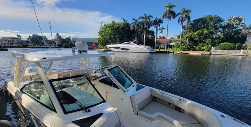  Yacht Photos Pics 2021 Boston Whaler 320 Vantage boat docked on a sunny waterfront with palm trees.
