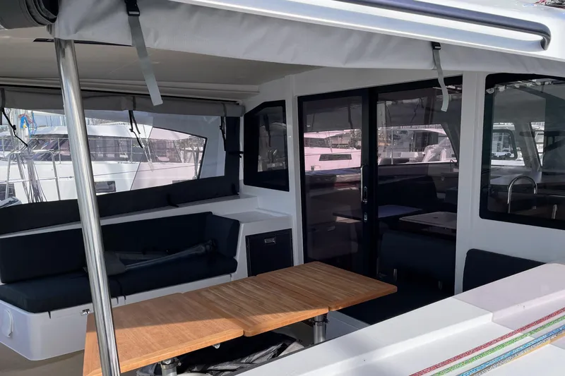  Yacht Photos Pics Outdoor seating area on a 2022 Nautitech 44 Open catamaran, featuring a wooden table and cushioned benches.