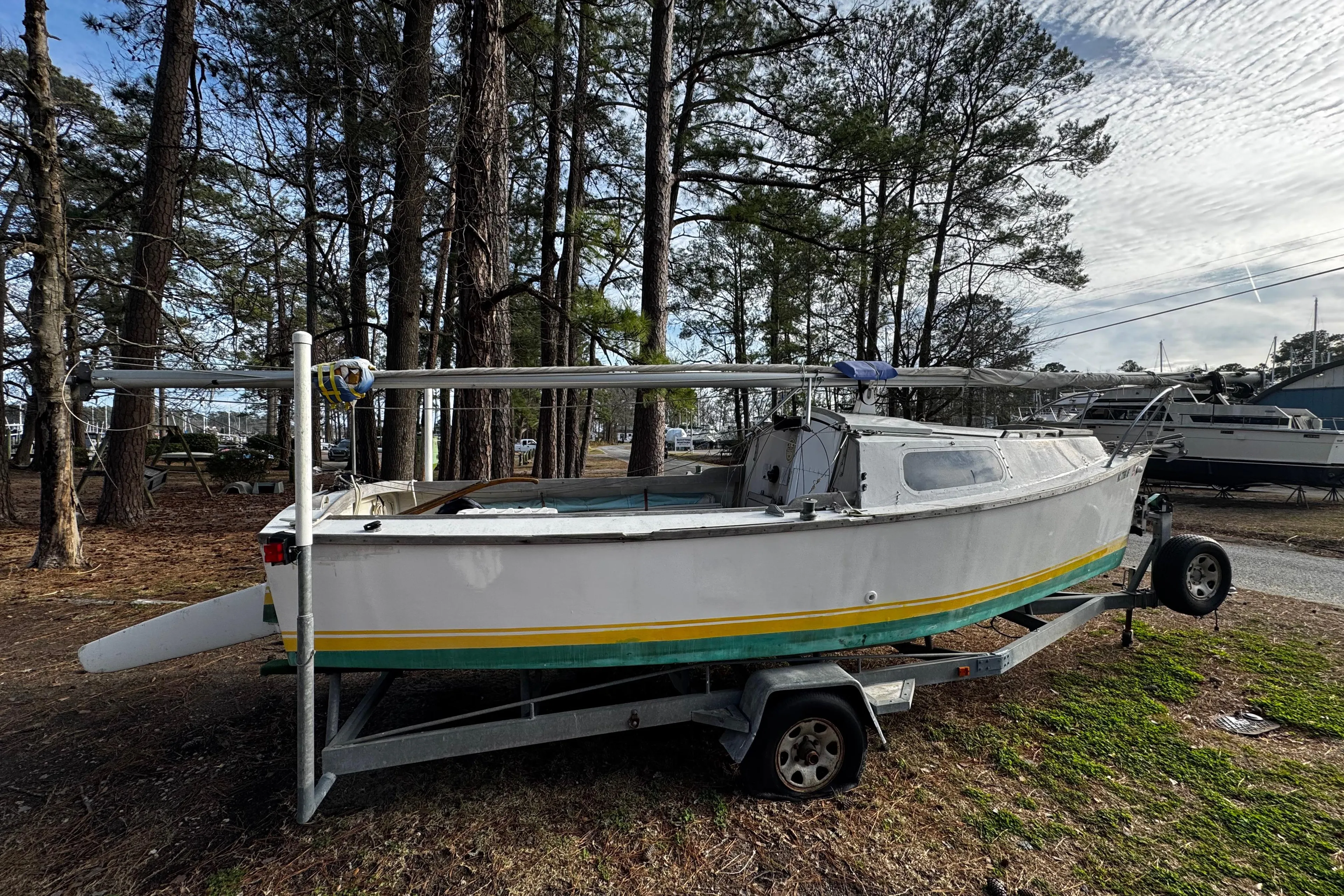 1976 Custom Wooden Sloop on trailer, surrounded by trees and parked outdoors.