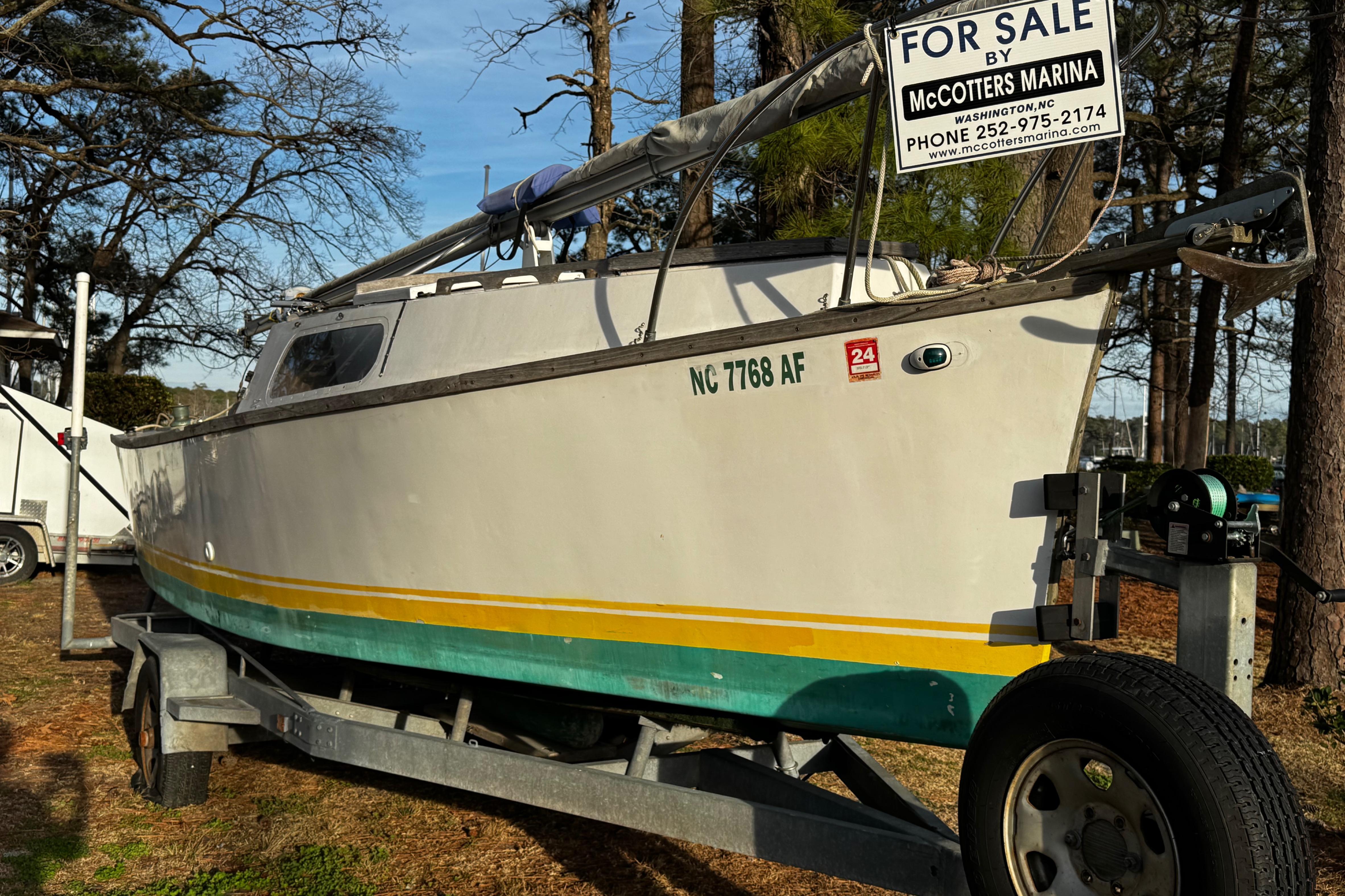 1976 Custom Wooden Sloop for sale at McCotters Marina, on trailer, forest background.