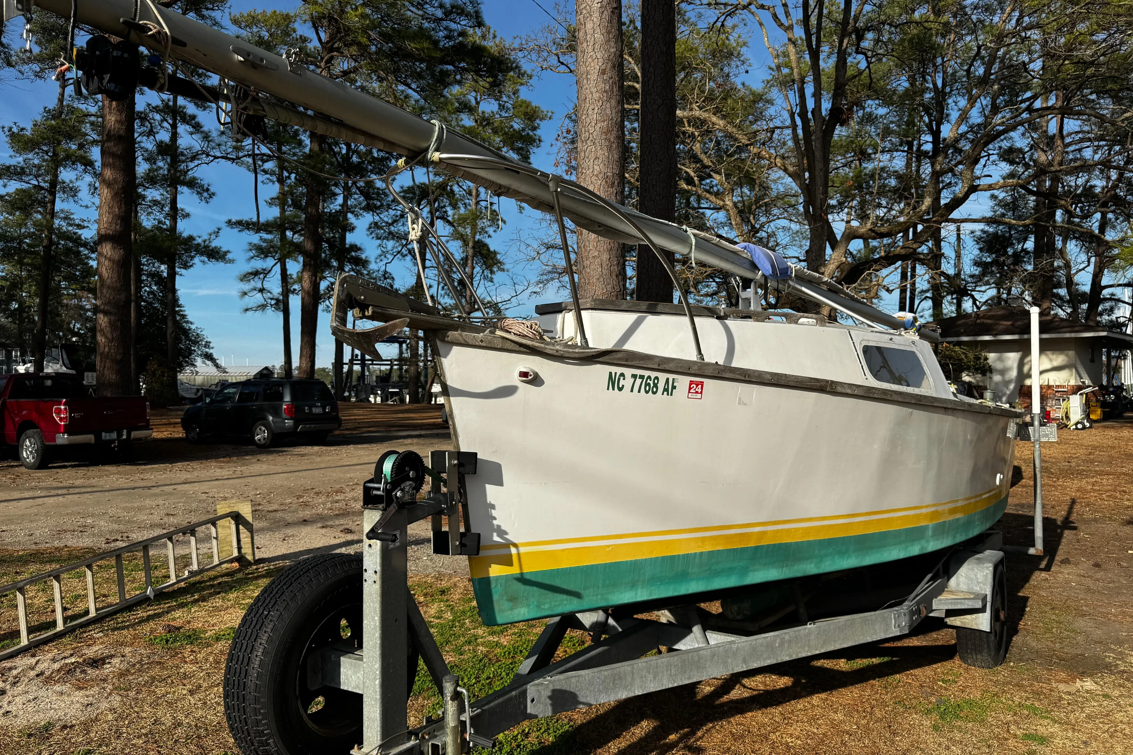 1976 Custom Wooden Sloop on trailer, surrounded by trees and parked vehicles.