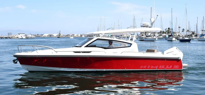 Mdr #297 In Stock Yacht Photos Pics Red 2024 Nimbus W9 boat cruising in a marina with sailboats in the background.