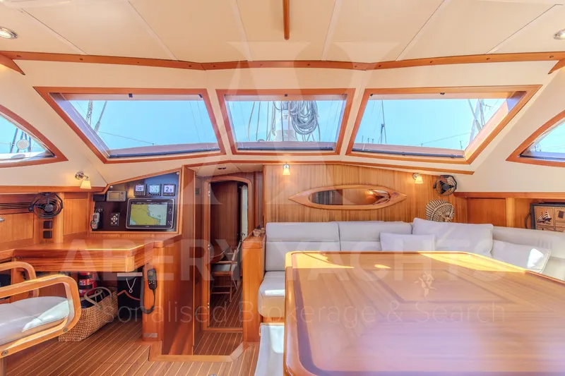 Satori Yacht Photos Pics Luxurious interior of a 2005 Farr 64 yacht with wooden finishes and large windows.