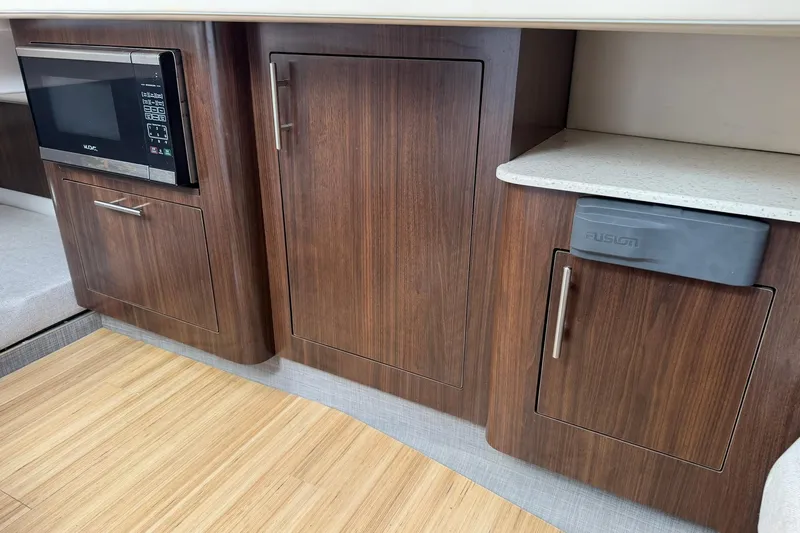  Yacht Photos Pics 2019 Regal 33 SAV interior with wood cabinetry, microwave, and Fusion audio system.